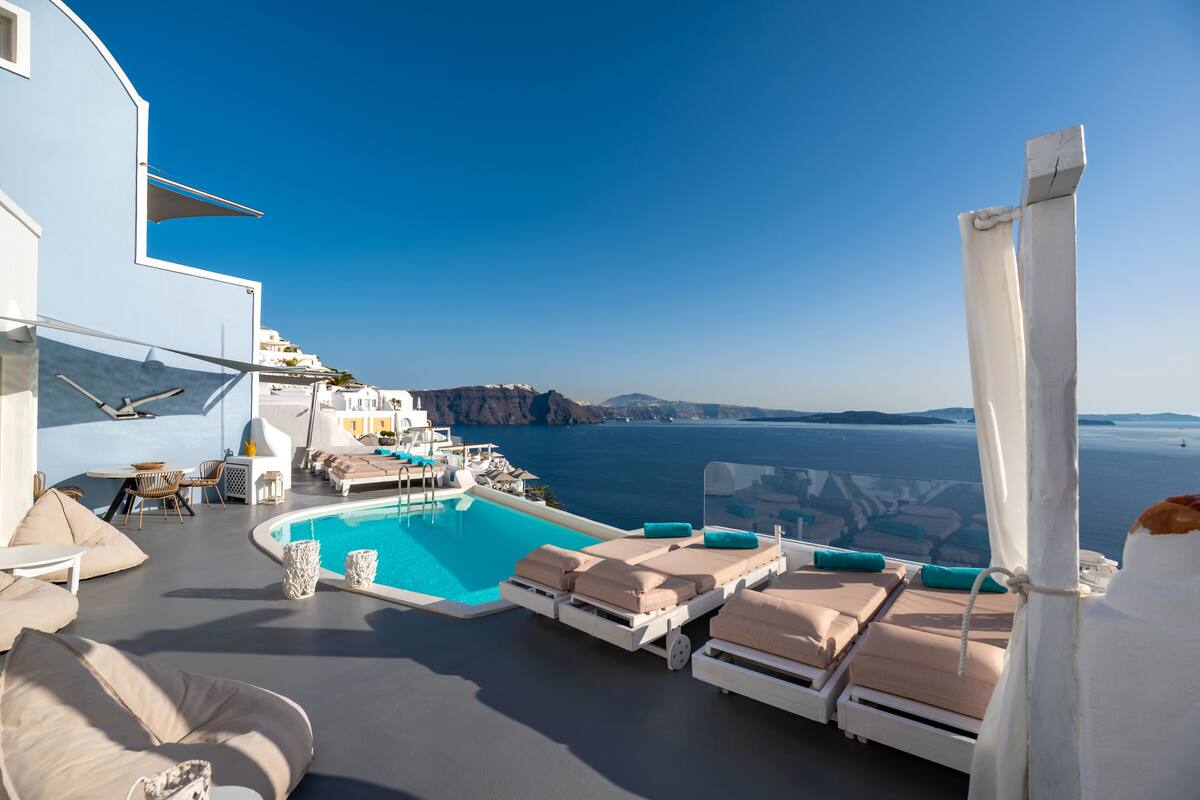 A rooftop pool area with lounge chairs and a view of the sea.
