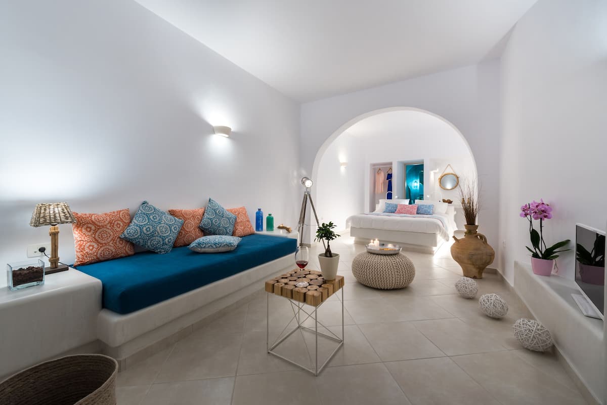 A modern living room with a blue sofa, white walls, and a central archway leading to another room.