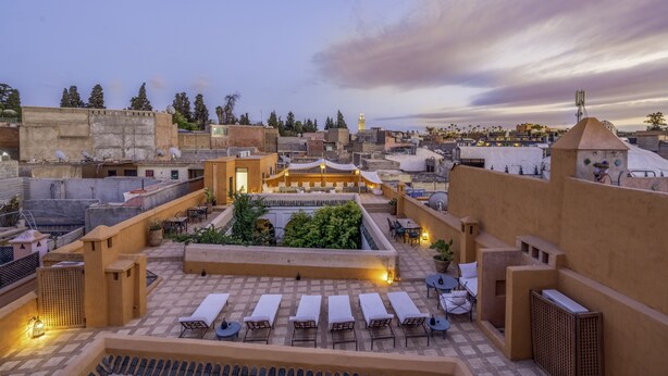 A rooftop terrace with lounge chairs, a small garden area, and a view of the cityscape. - Riad Dar Sara (Marrakech)