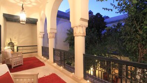 A balcony with red carpets, white furniture, and decorative lighting. - Riad Dar Sara (Marrakech)