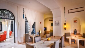A dining area with a long table, multiple chairs, and a decorative wall with a framed picture. - Riad Dar Sara (Marrakech)