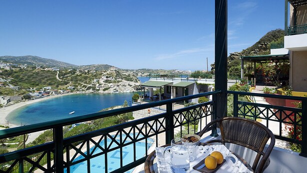 A balcony with a view of a coastal area, including a beach and a pool.