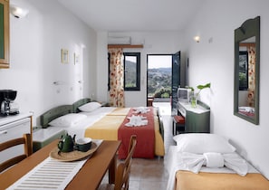 Habitación de hotel con dos camas, zona de comedor, televisor y balcón con vistas.