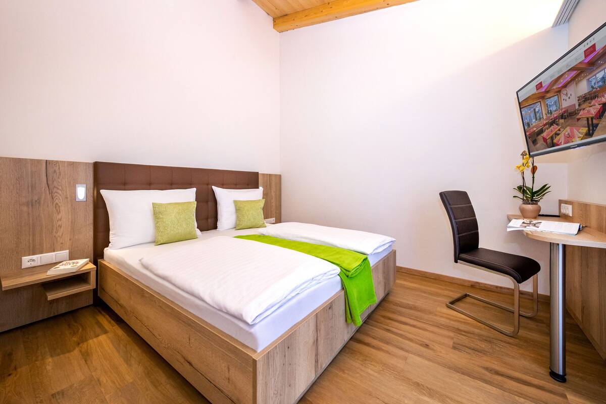 Une chambre d’hôtel moderne avec un lit en bois, un bureau et une chaise.