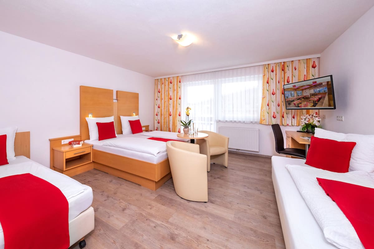 Une chambre d’hôtel avec un grand lit, deux tables de chevet, un bureau, une chaise et un téléviseur.
