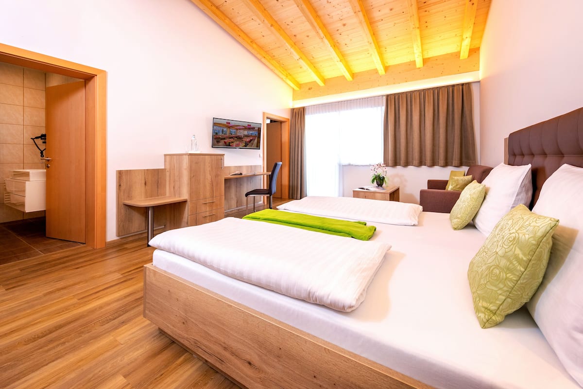 Une chambre d’hôtel moderne avec un lit en bois, un bureau et un espace douche.