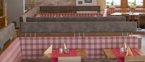 A restaurant with wooden booths and tables, red tablecloths, and a stone wall with framed pictures.