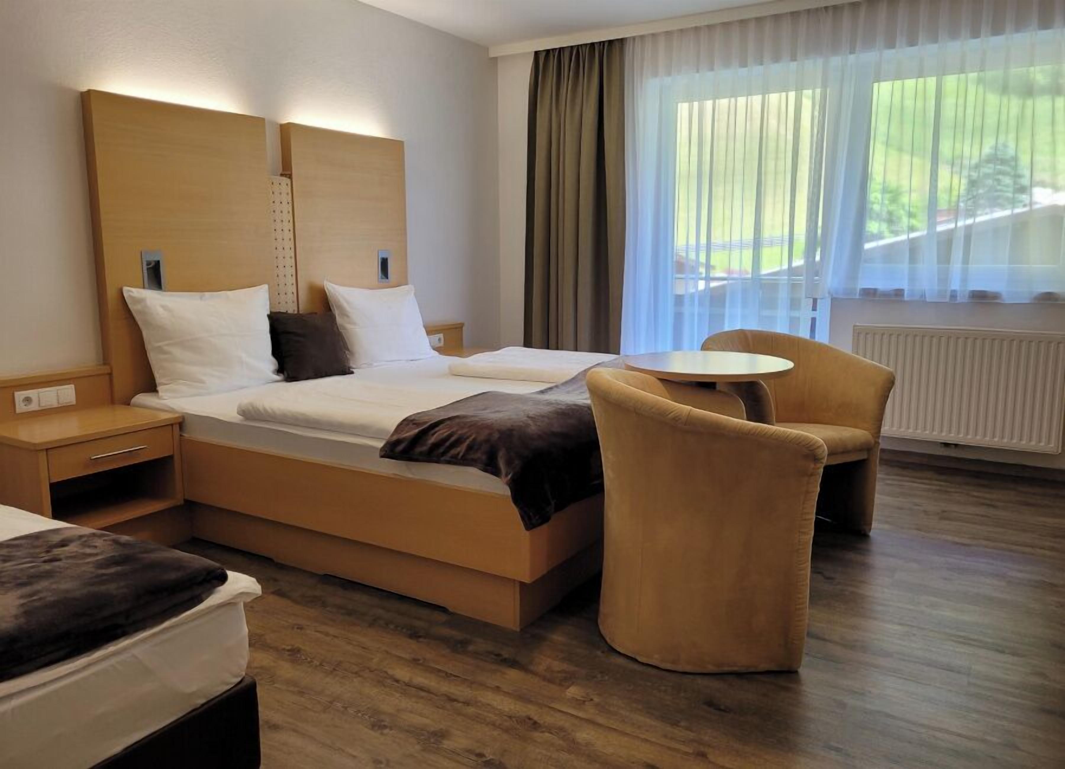 Een moderne hotelkamer met een groot bed, een nachtkastje, een stoel en een kleine tafel.