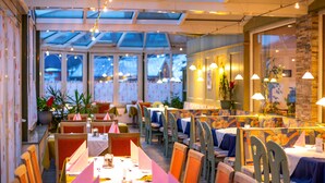 A restaurant with a long table, chairs, and hanging lights.
