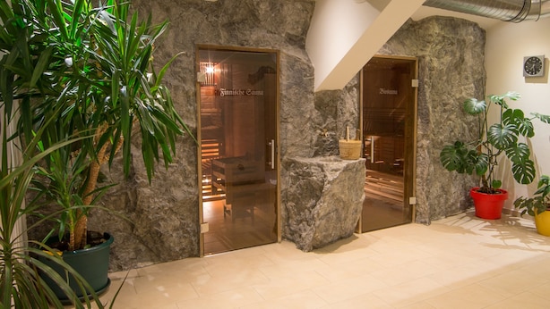 A spa entrance with stone walls, a wooden door, and potted plants.