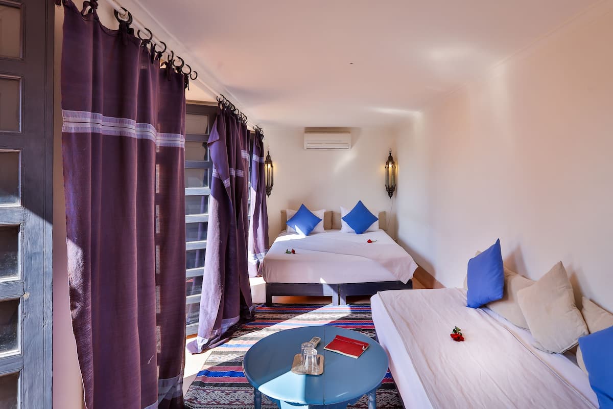 A hotel room with a bed, a small table, and a chair.