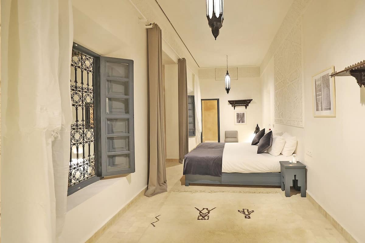 A hotel room with a bed, a nightstand, a lamp, and a decorative wall piece.