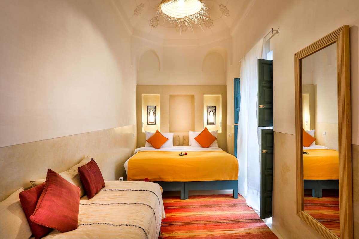 A hotel room with two beds, a large mirror, and a ceiling light fixture.