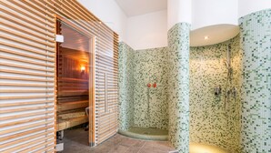 A modern bathroom with a mosaic tile shower, wooden slatted walls, and a bench. - Hotel Badhaus (Zell am See)