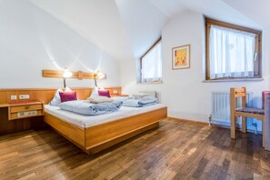 Ein Schlafzimmer mit einem hölzernen Bett, Nachttischen, einem Sessel und einem Fenster mit Vorhängen.
