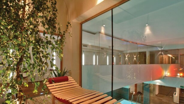 A modern interior with a wooden bench, a glass partition, and a view of the outside. - Hotel Badhaus (Zell am See)