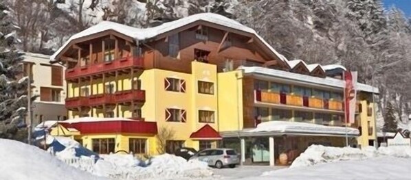 Un hotel de varios pisos con balcones, un telesilla y un paisaje nevado.