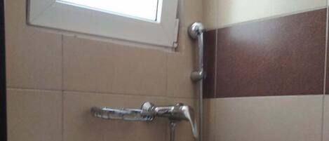 A bathroom with a toilet, a shower, and a window.