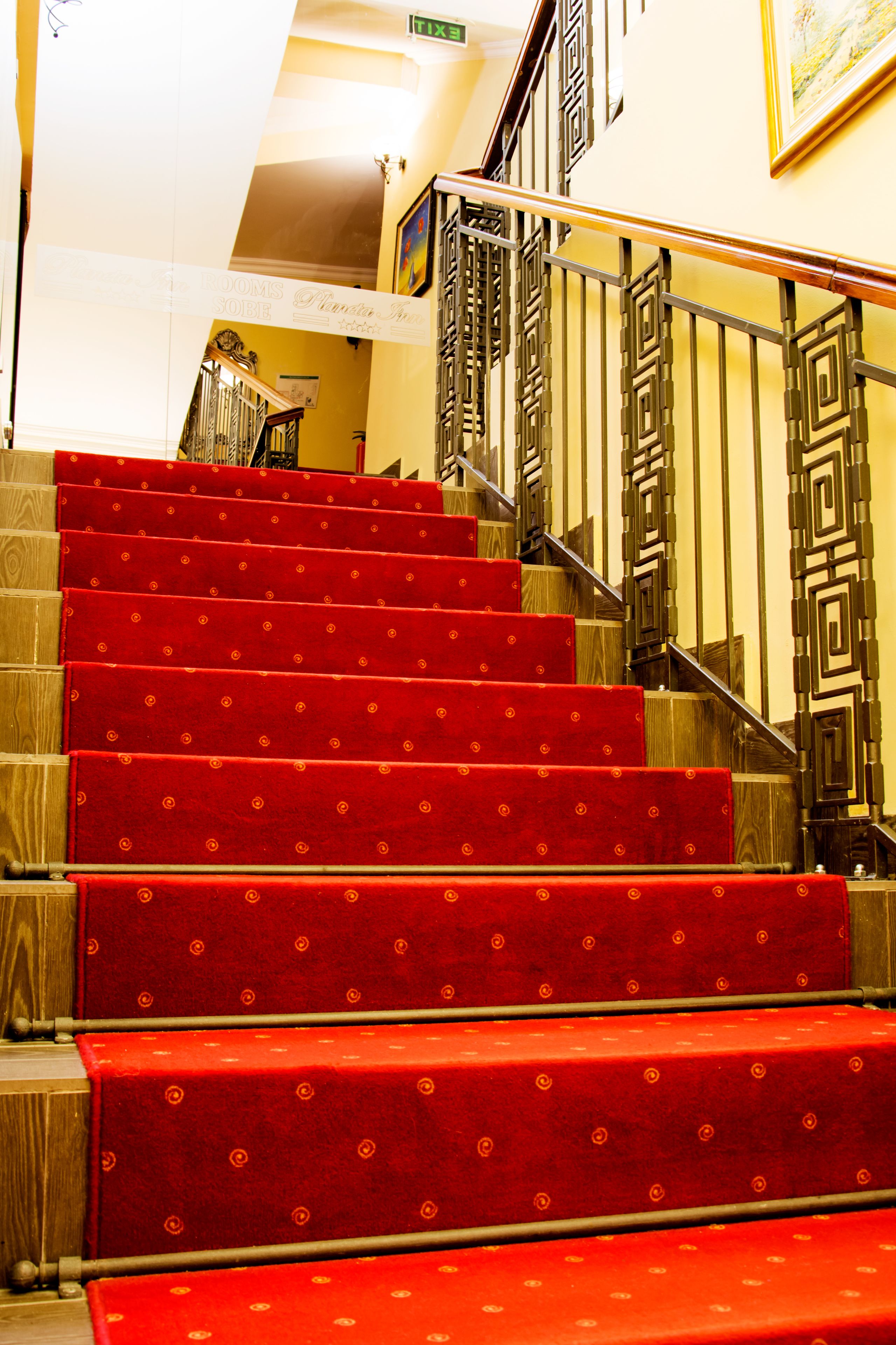 A staircase with red carpeted steps and a wooden handrail.