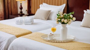 A hotel room with two beds, a vase with flowers, a tray with a cup and a glass of wine, and a lamp in the background. - Planeta Inn Hotel (Novi Sad)