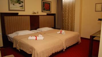 A hotel room with two beds, a wooden headboard, a red carpet, and artwork on the walls.