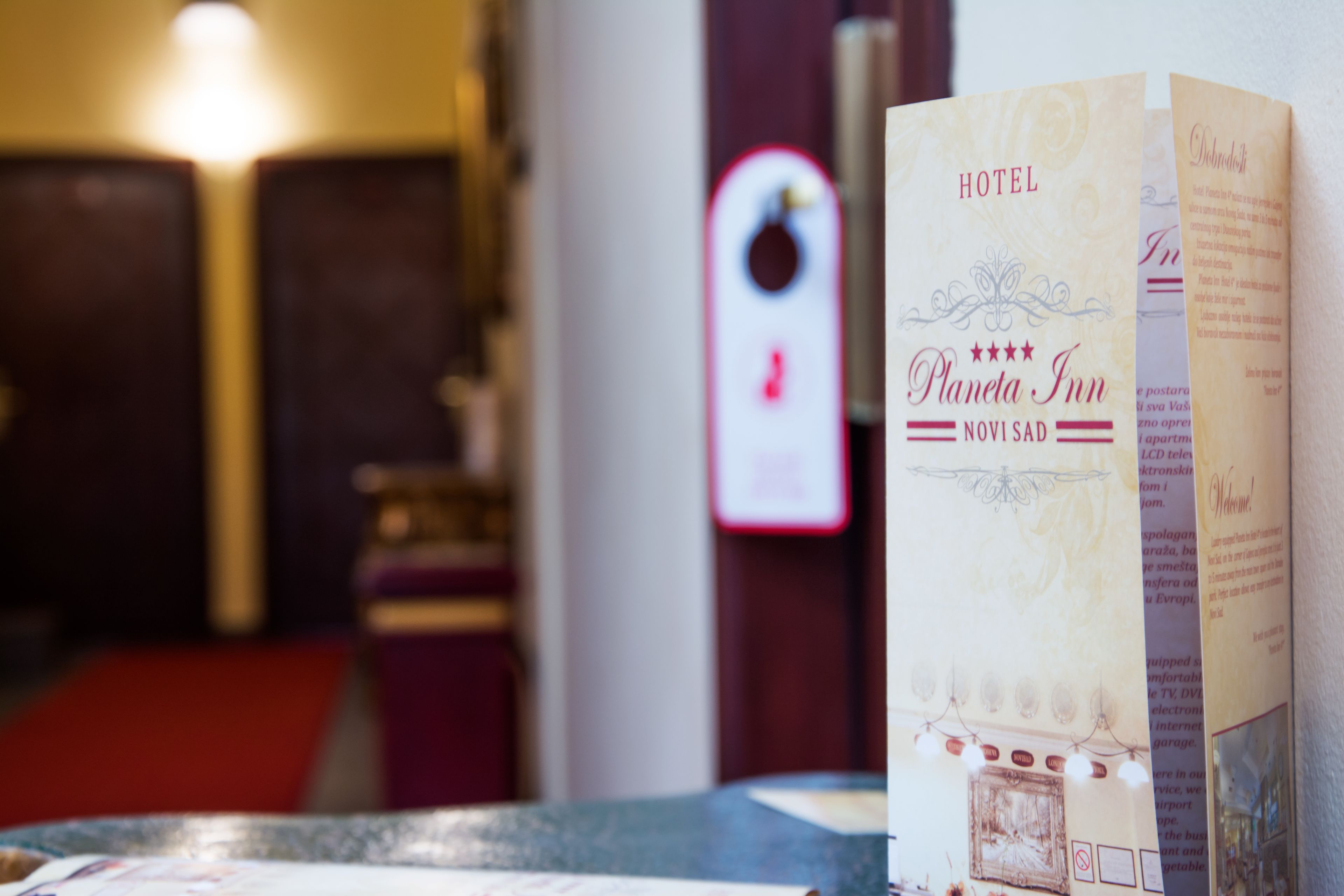 Un folleto de hotel titulado 'Planet Inn' con texto visible y una vista parcial del interior que incluye una puerta y una alfombra roja.