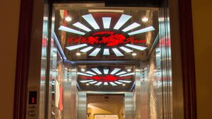 An elevator with a digital display, marble walls, and a red logo on the ceiling. - Planeta Inn Hotel (Novi Sad)