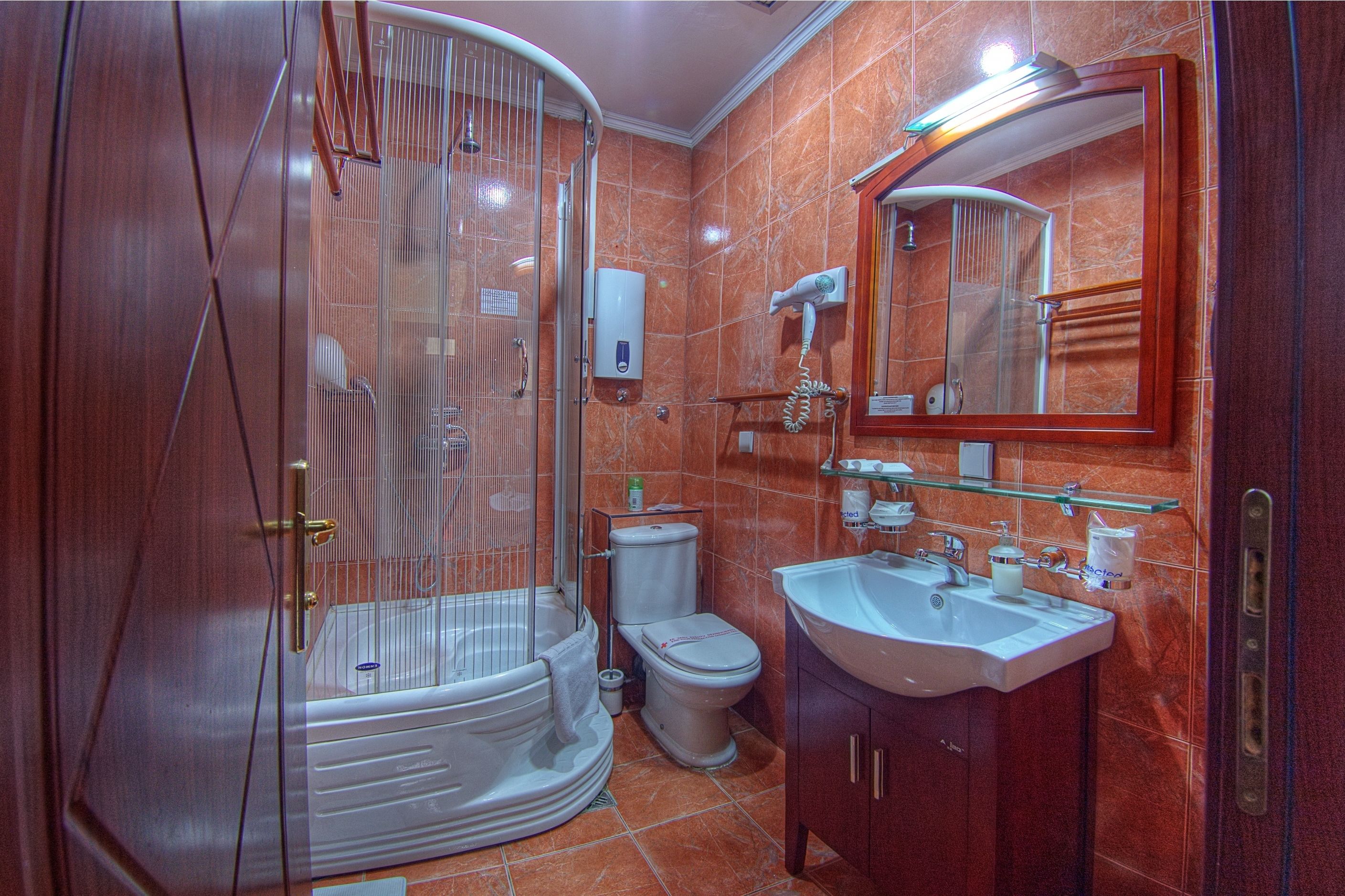 Un baño con ducha envuelta en vidrio, inodoro, lavamanos y espejo.
