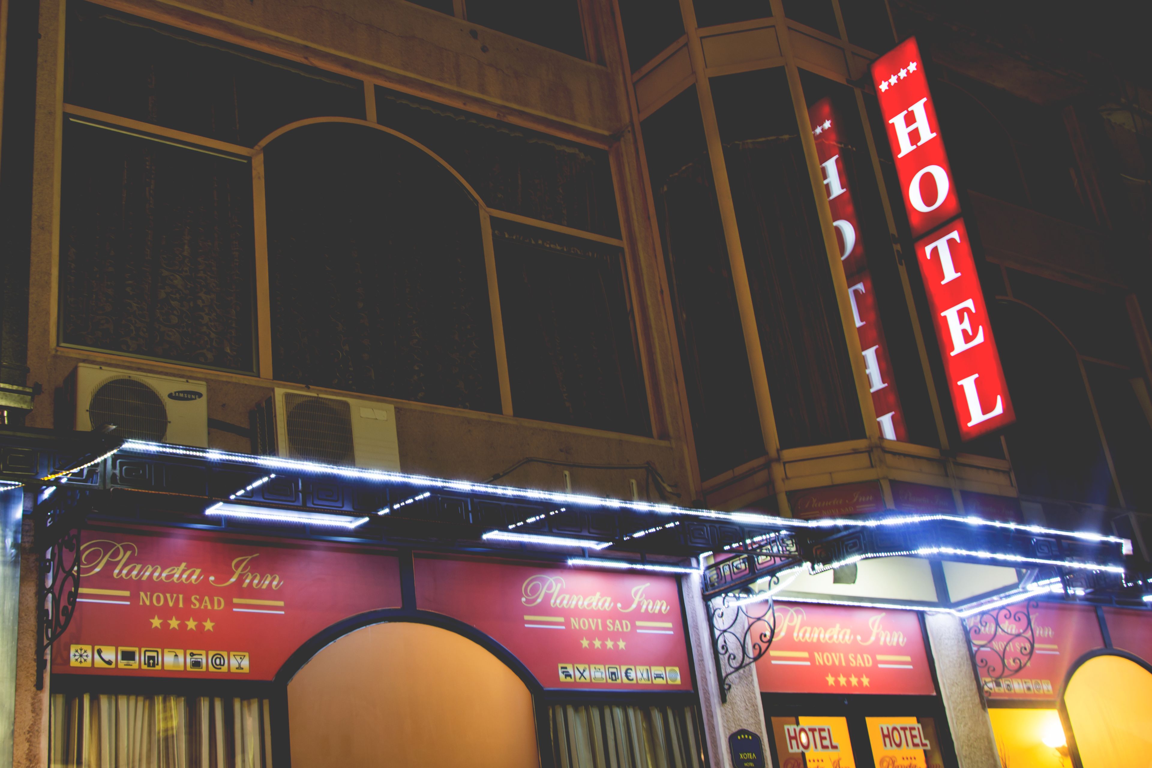 Un letrero de hotel con el nombre 'Hotel' y un letrero de neón que dice 'Planetia Inn' con una calificación de 5 estrellas.