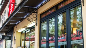A hotel with a red sign, large windows, and a red carpet entrance. - Planeta Inn Hotel (Novi Sad)