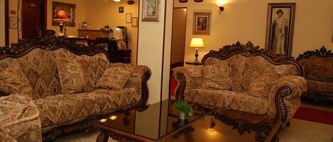 A room with two patterned sofas, a glass coffee table, and a mirror reflecting the room.