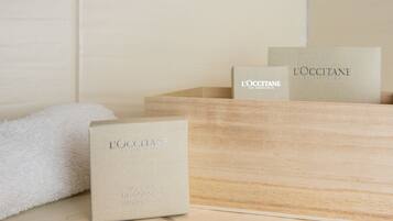 A wooden box with a white towel and two smaller boxes with 'L'OCCITANE' branding.