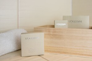 A wooden box with a white towel and two smaller boxes with 'L'OCCITANE' branding.