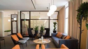 A modern lounge area with a sofa, chairs, a coffee table, and potted plants.