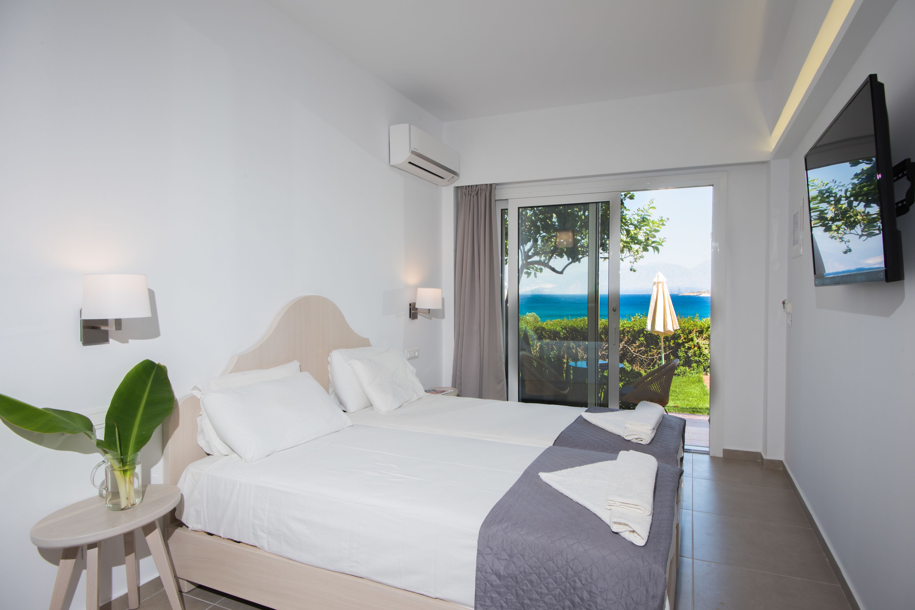 Ein Schlafzimmer mit zwei Betten, einem Fernseher und Meerblick.