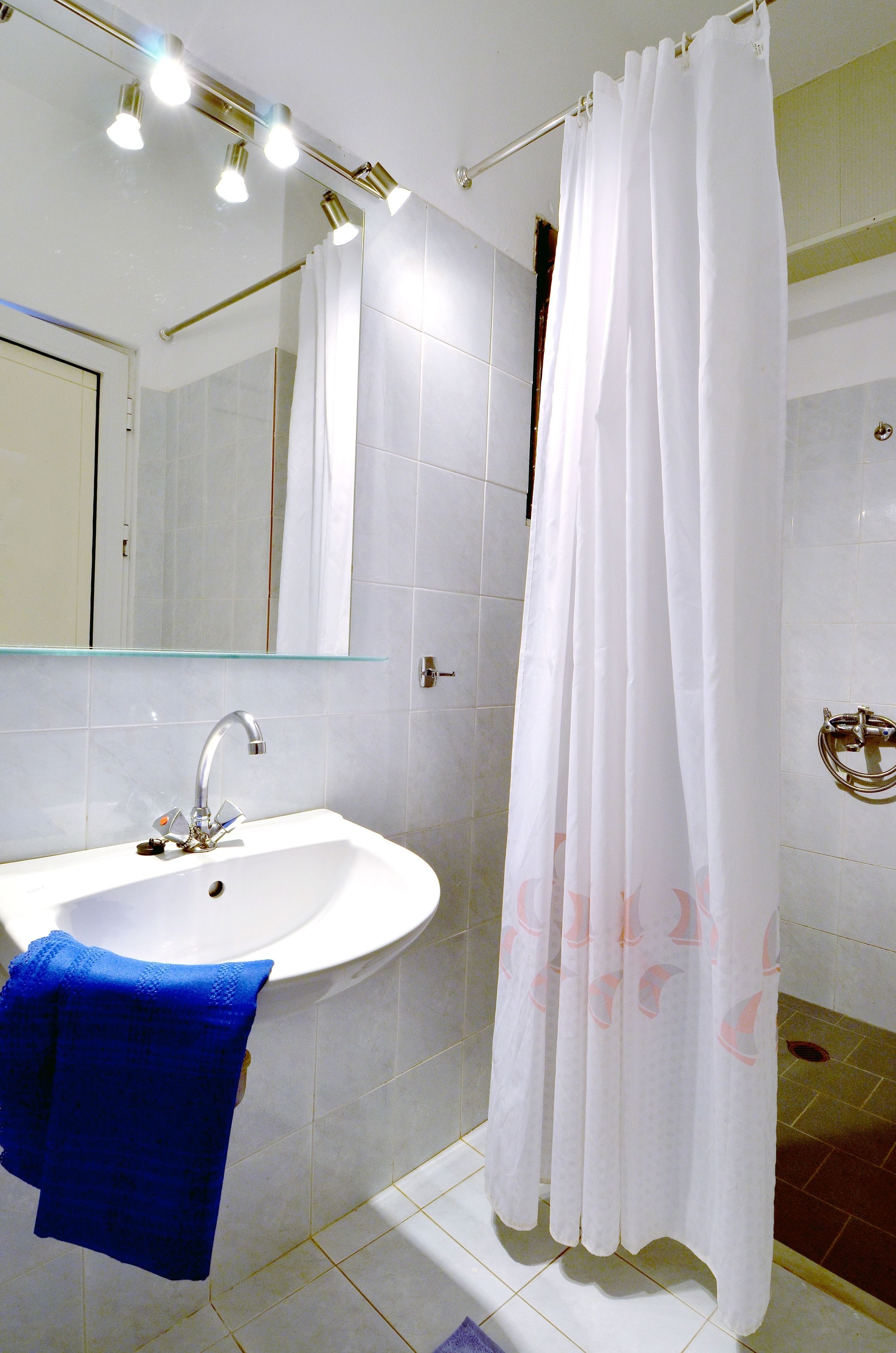 Un baño con lavamanos blanco, espejo y cortina de ducha.