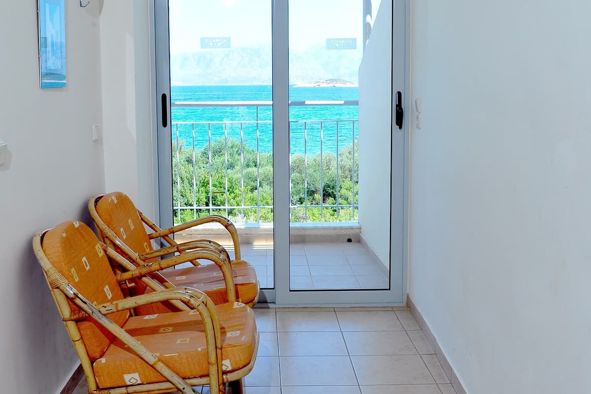 Ein Balkon mit Meerblick, zwei Korbstühle und eine weiße Badewanne.