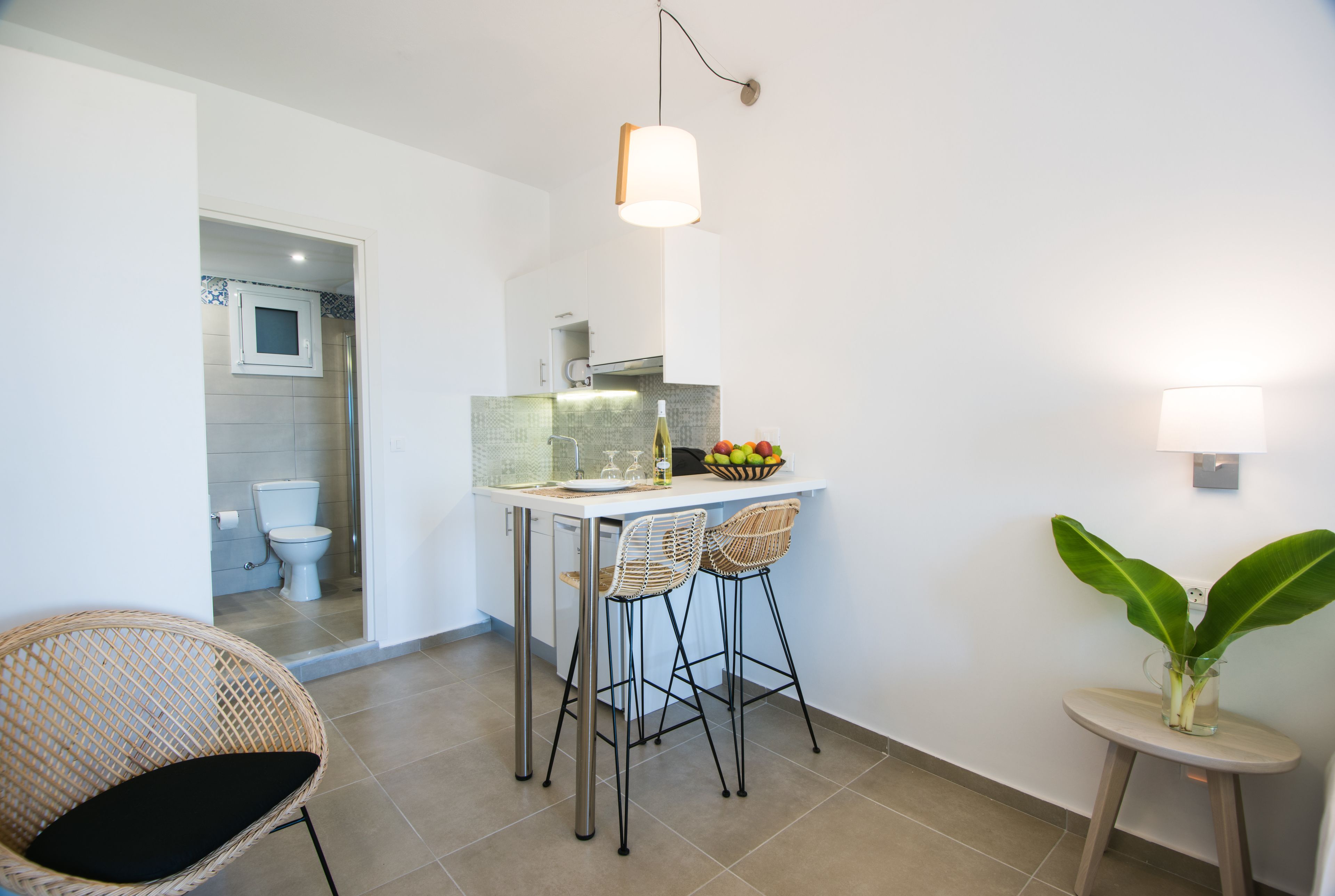 A compact kitchen with a dining area, including a small table, two chairs, and a potted plant.