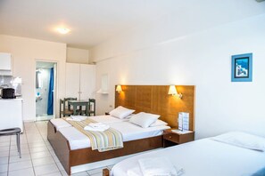 A hotel room with a bed, bedside table, and a small desk with a chair. There is a bathroom visible through an open door. - Mirabella Apartments (Agios Nikolaos)