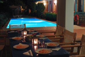 A dining table set for a meal with plates of food, glasses, and a candle. - Mirabella Apartments (Agios Nikolaos)