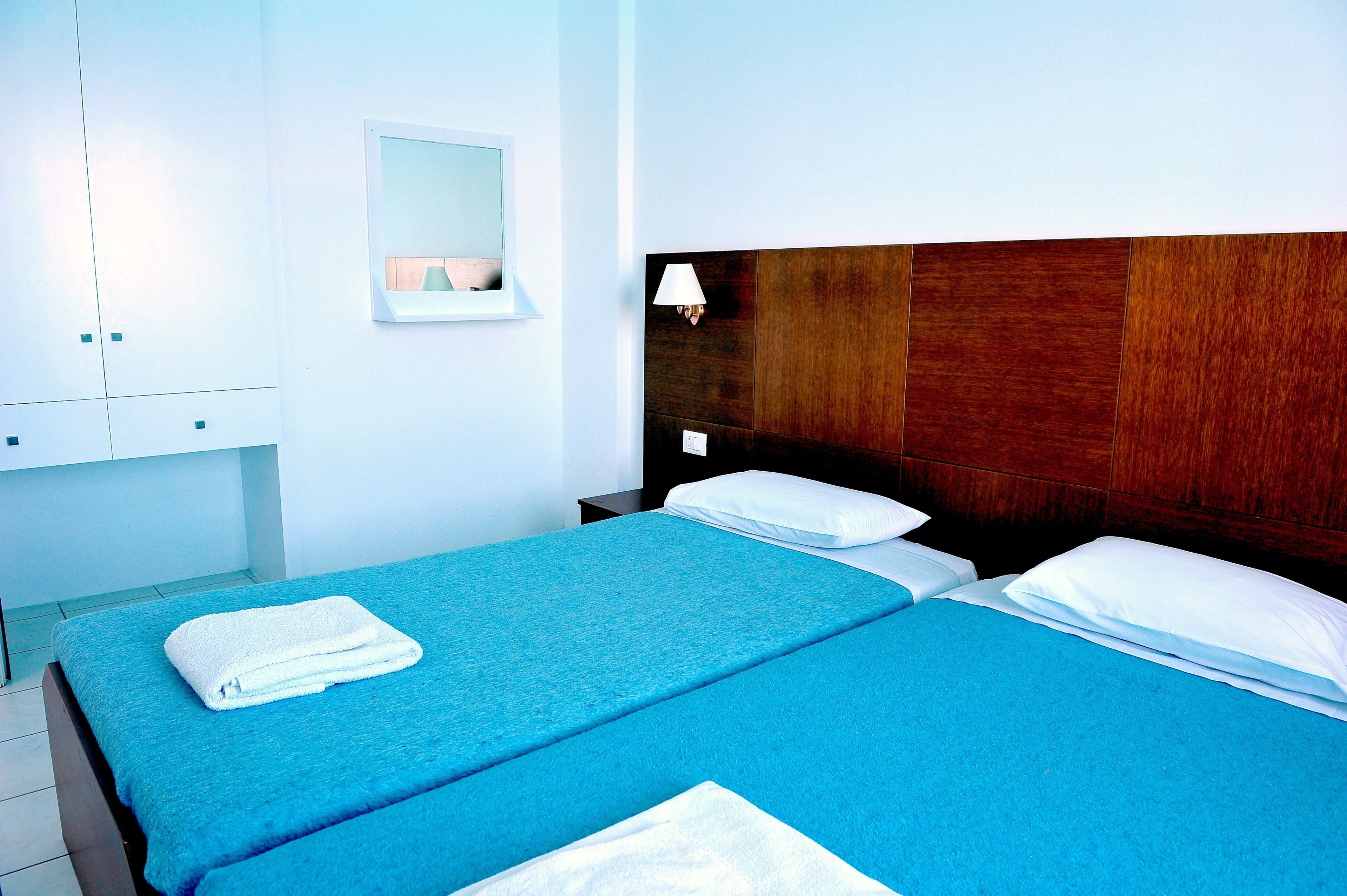 Ein Hotelzimmer mit Bett, Nachttisch, Lampe und Spiegel.