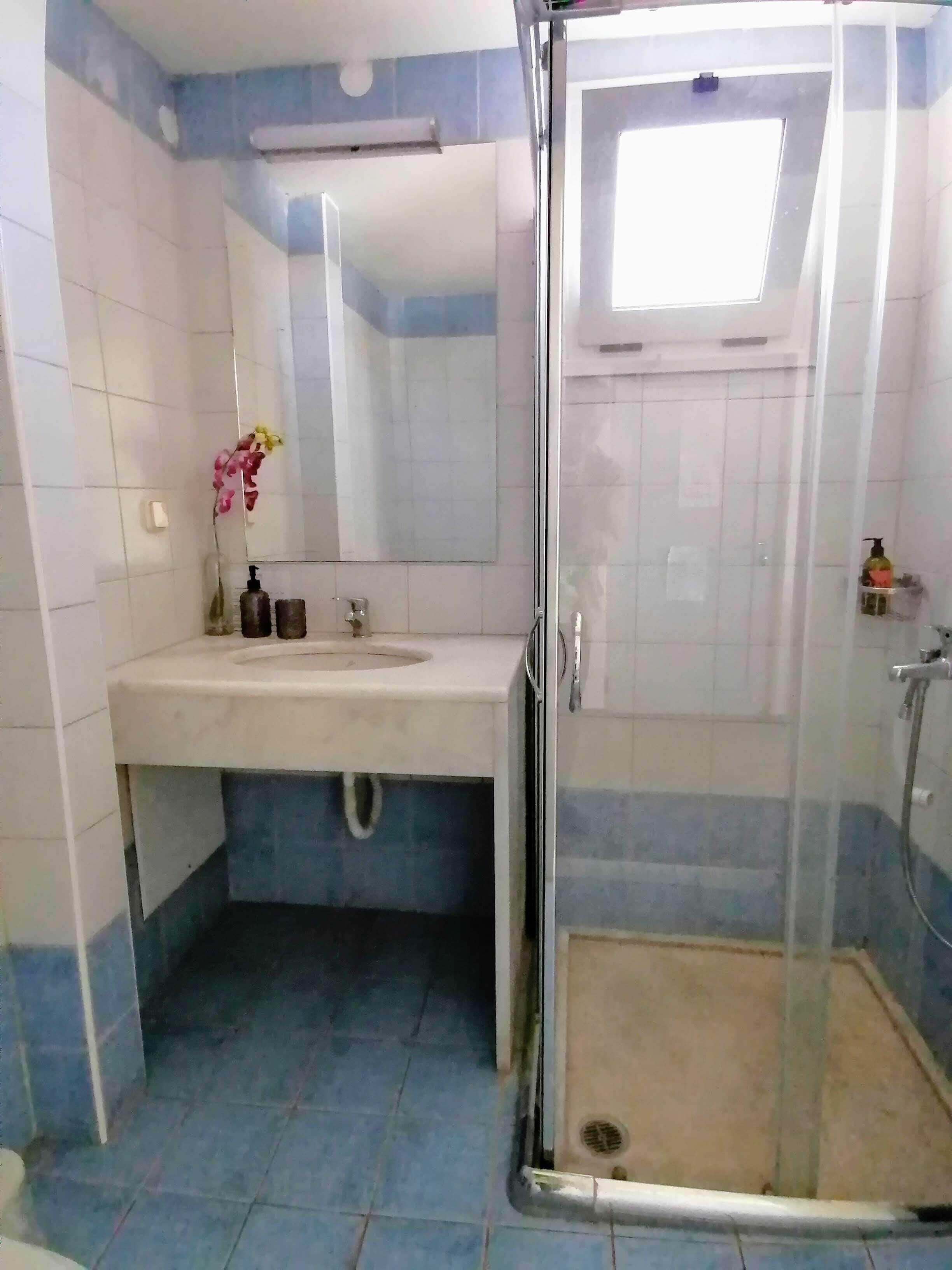 A bathroom with a sink, mirror, and glass shower enclosure.