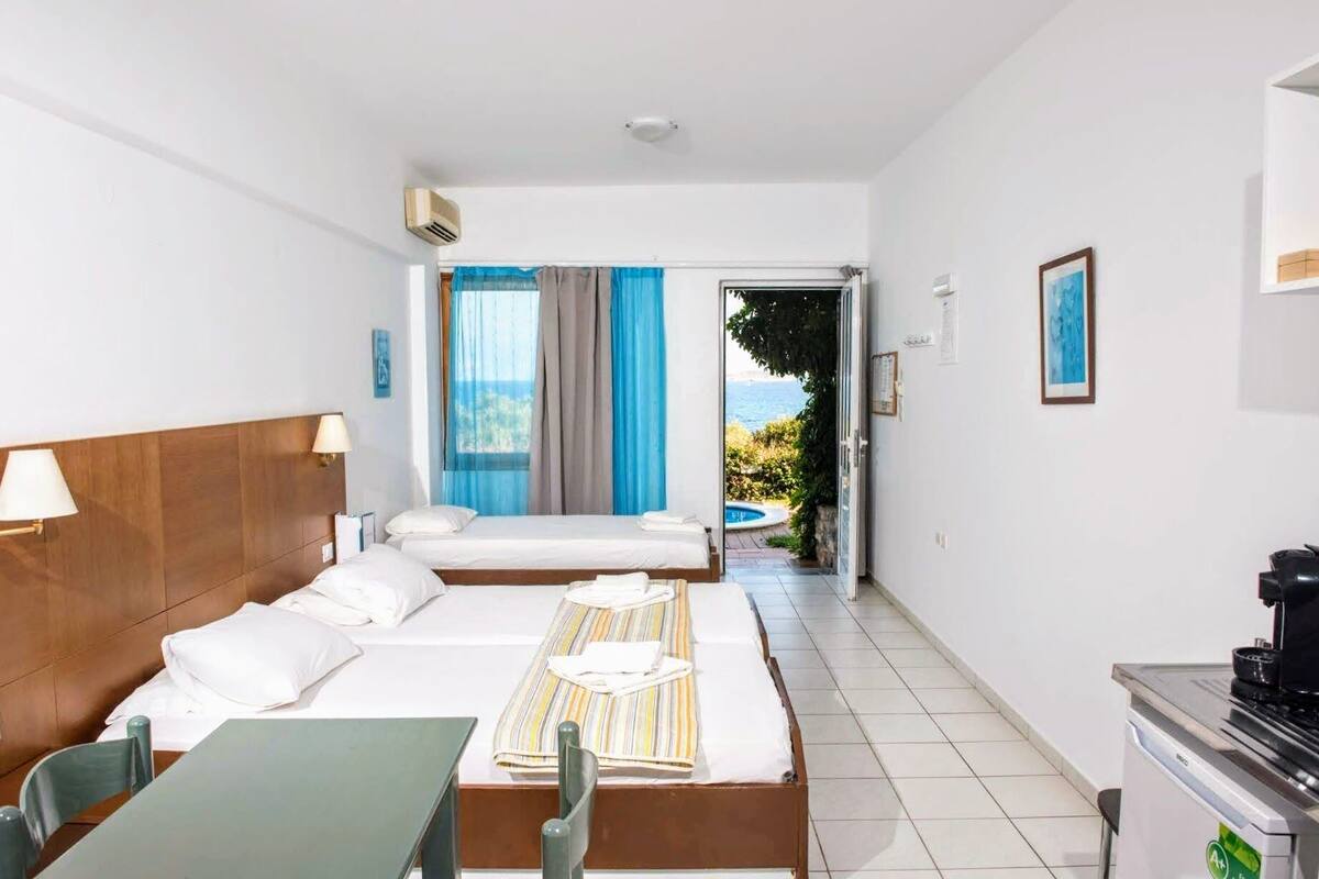 Ein Hotelzimmer mit zwei Betten, einem Esstisch und Meerblick.