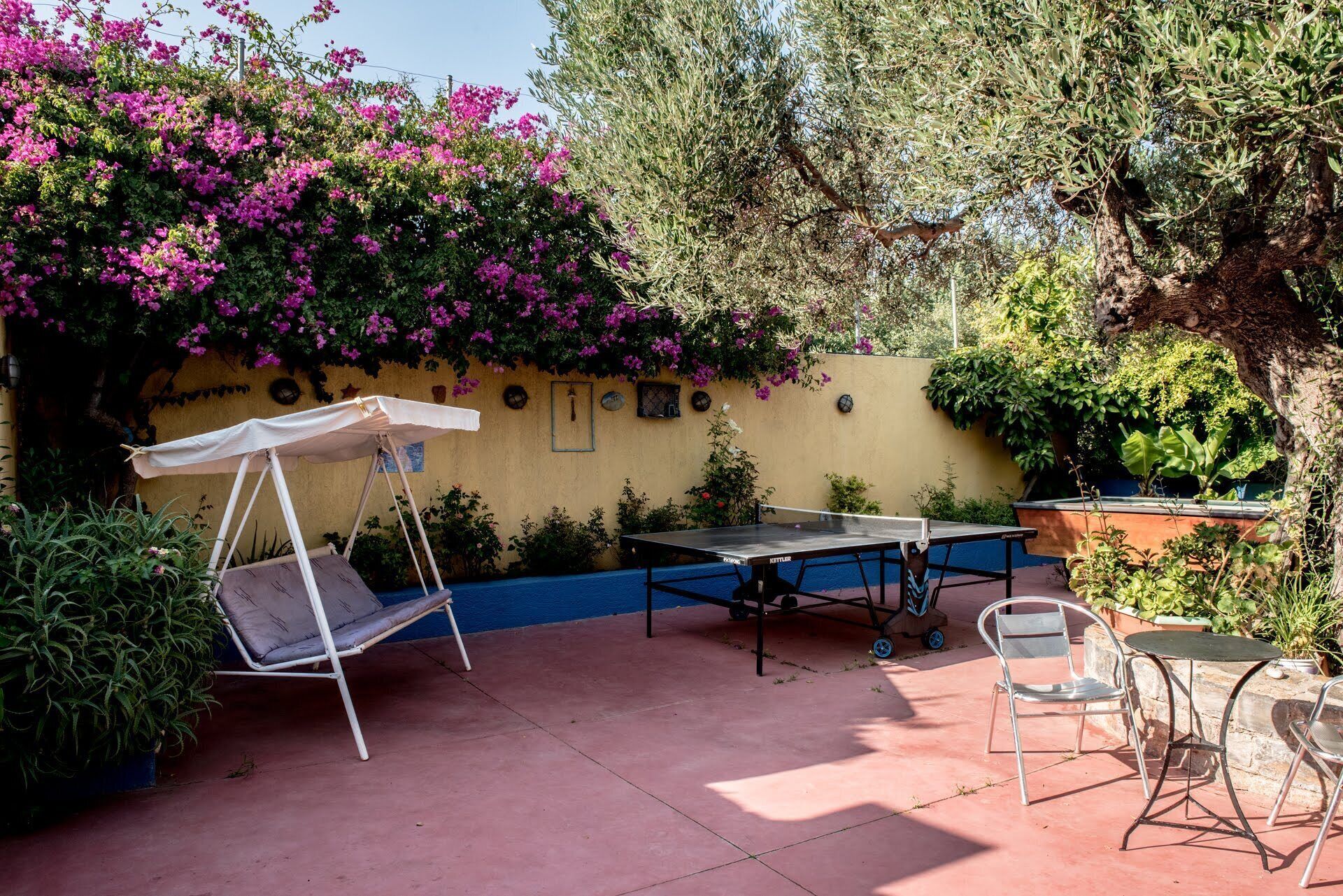 Eine Außenpatio mit Tischtennisplatte, einer Schaukelstuhlsitzgelegenheit und einem Tisch mit Stühlen.