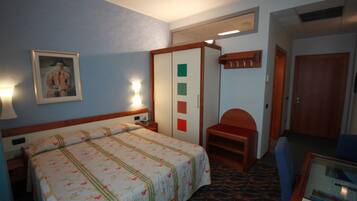 Una habitación de hotel con una cama, un escritorio, una silla y un armario.