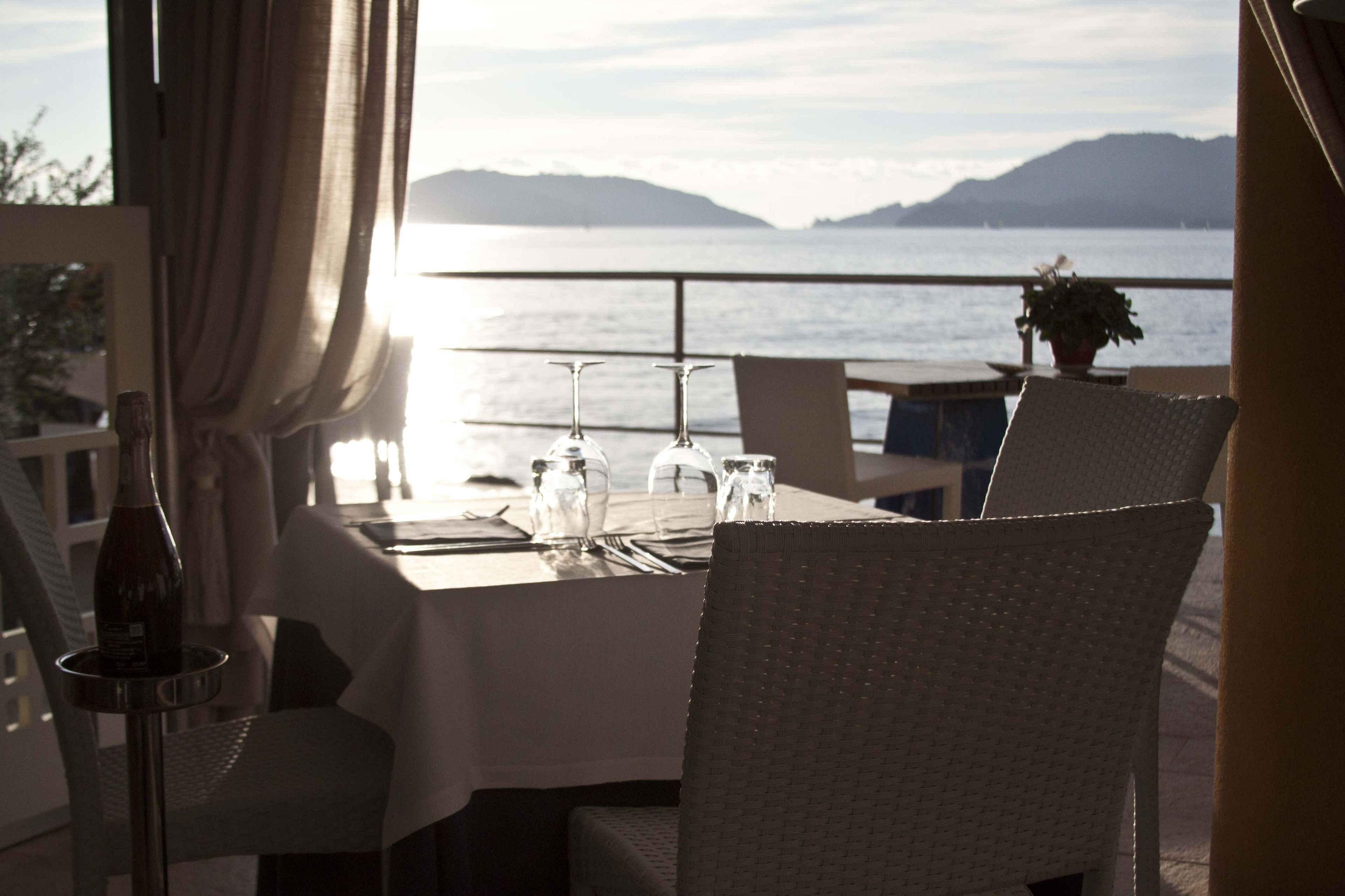 Une table dressée pour deux personnes, avec vue sur la mer et les montagnes.