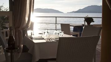 Une table dressée pour deux personnes, avec vue sur la mer et les montagnes.