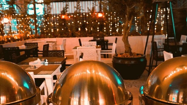 A restaurant with outdoor seating, including tables and chairs, and a large decorative tree. - Torino Amman Hotel (Amman)