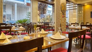 A restaurant with tables set for dining, chairs, and a large window offering a view of the outside. - Torino Amman Hotel (Amman)