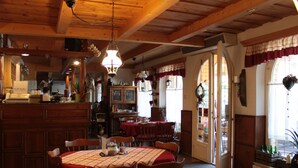 Un restaurante acogedor con vigas de madera, una zona de bar y un espacio para comer con mesas y sillas.